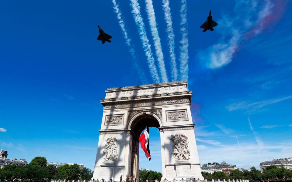 Two F22 of the US Air Force fly over the Arc de Triomphe on the Champs Elysees Avenue in Paris - AFP