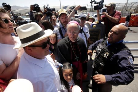 El Paso Bishop Mark Seitz talks to U.S. Customs and Border Protection officers while accompanying Honduran migrant Cesia and her parents at the Paso del Norte international border crossing bridge to help them to ask for asylum in El Paso, Texas, U.S. as se