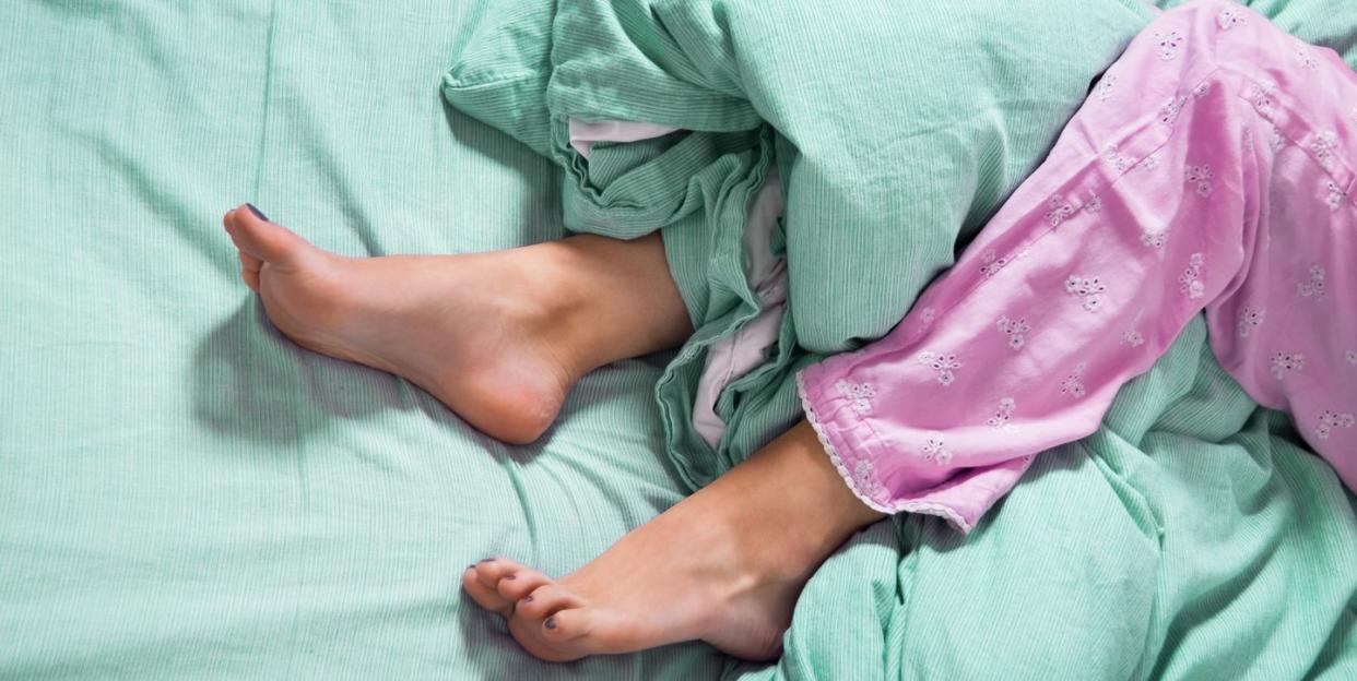 Bare Feet of a Young Woman on Blue Bed