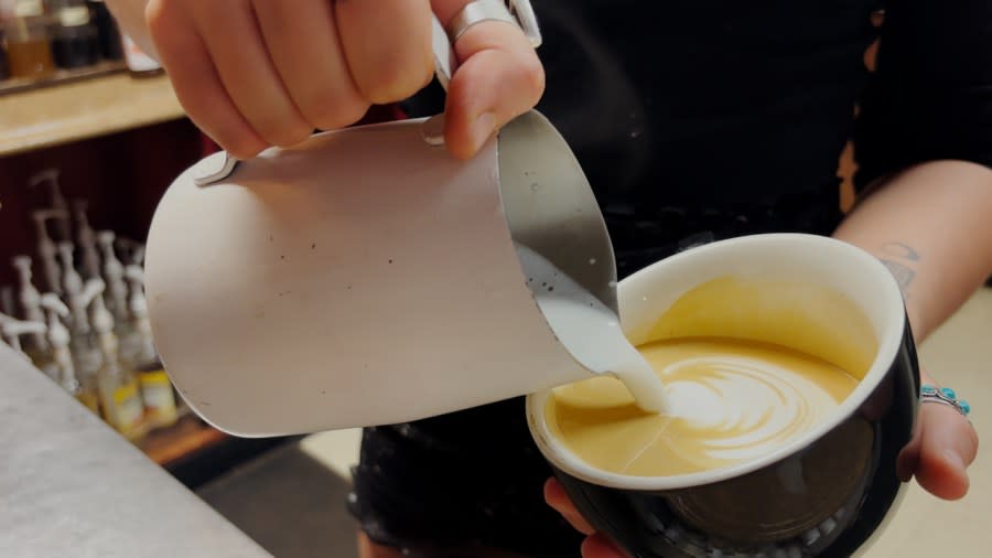One barista poured a latte with a pretty design for customers to enjoy.
