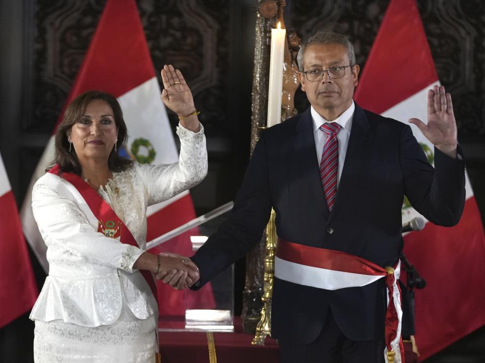 Peru's President Dina Boluarte and newly named Chief of Staff Pedro Angulo hold up their right hands during a swearing-in ceremony for her cabinet members, at the government palace in Lima, Peru, Saturday, Dec. 10, 2022. (AP Photo/Guadalupe Pardo)