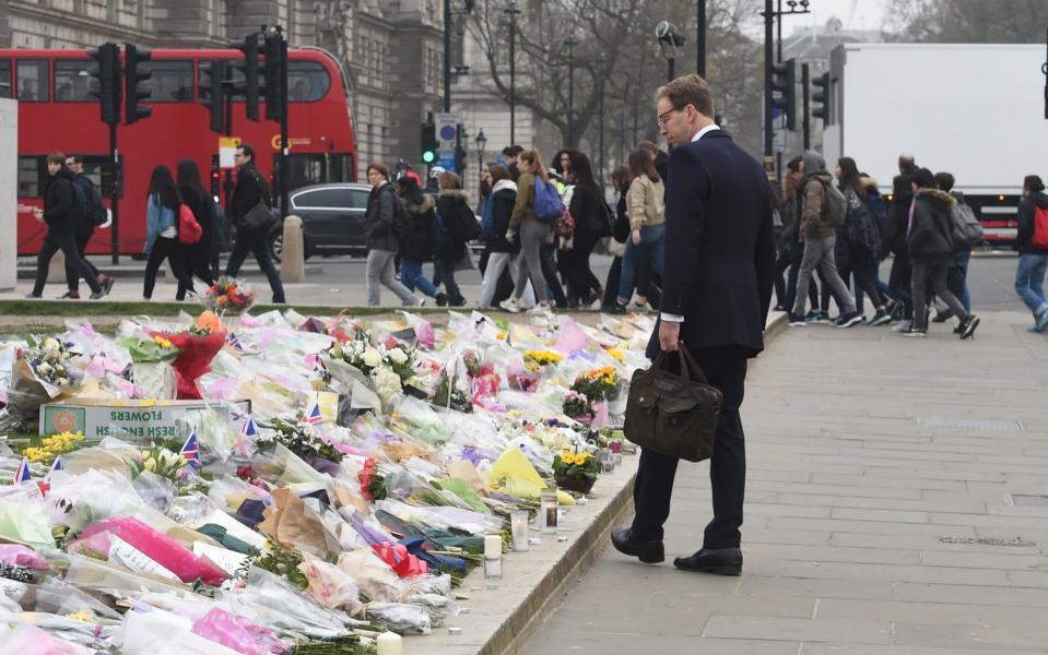 Hero MP Tobias Ellwood looks at floral tributes at the Palace of Westminster gates, where Pc Keith Palmer died - Evening Standard / eyevine