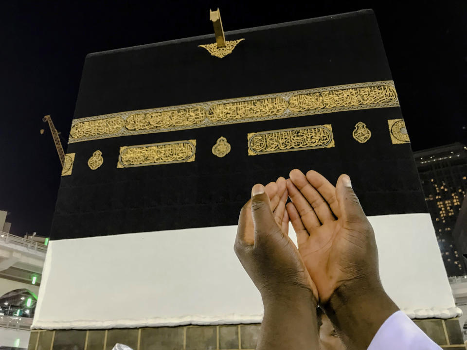 A Muslim pilgrim, only hands seen, prays near the Kaaba, the cubic building at the Grand Mosque, ahead of the annual Hajj pilgrimage, in the Muslim holy city of Mecca, Saudi Arabia, Friday, Aug. 17, 2018. The annual Islamic pilgrimage draws millions of visitors each year, making it the largest yearly gathering of people in the world. (AP Photo/Dar Yasin)