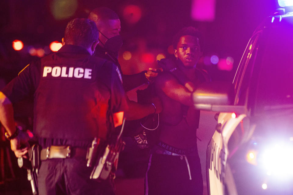 A man is arrested while out a few hours past curfew in Miami Beach, Fla., on Sunday, March 21, 2021. An 8 p.m. curfew has been extended in Miami Beach after law enforcement worked to contain unruly crowds of spring break tourists. (Daniel A. Varela/Miami Herald via AP)