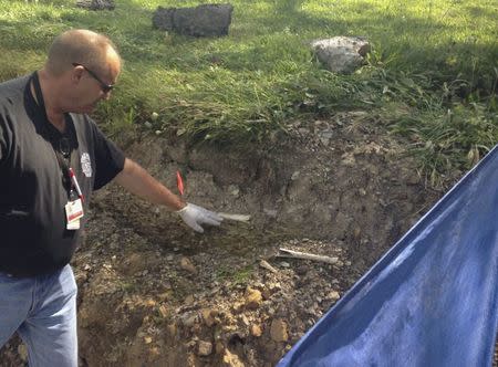 Schuylkill County Deputy Coroner Joe Pothering points to human bones in embankment along Route 61 in Schuylkill Haven, Pennsylvania August 14, 2015. REUTERS/David DeKok