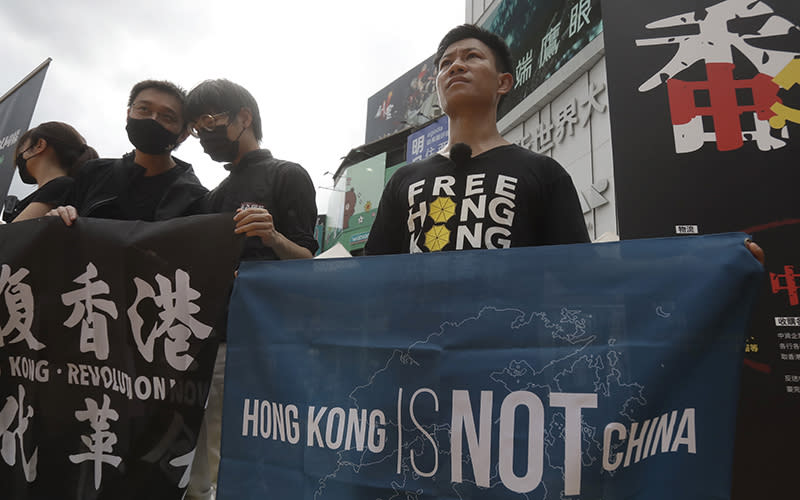 An activist holds a fabric banner that reads "Hong Kong is not China" as other protesters stand nearby.