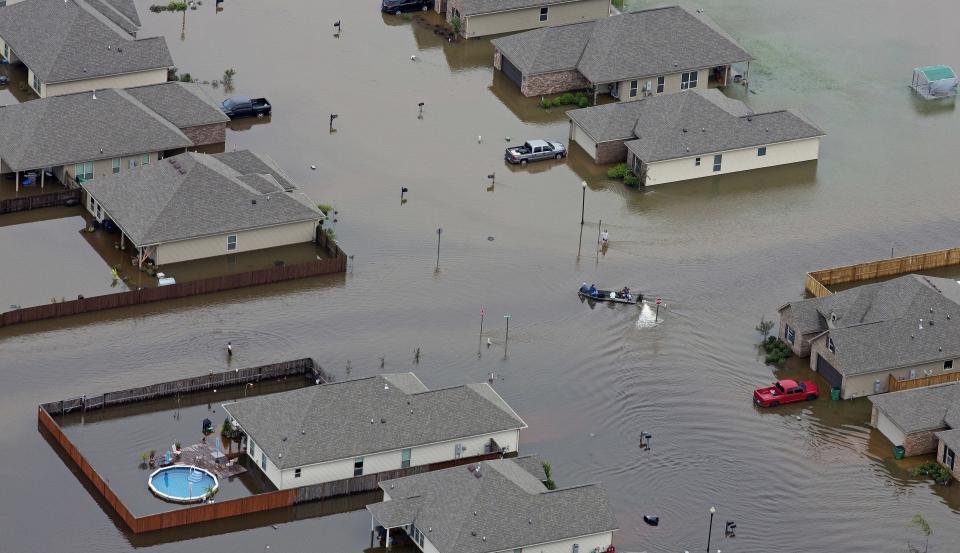 FILE- A boat motors between flooded homes after heavy rains inundating the region, in Hammond, La., on Aug. 13, 2016. A new study Thursday, May 18, 2023, finds the natural burst of El Nino warming that changes weather worldwide is far costlier with longer-lasting expenses than experts had thought, averaging trillions of dollars in damage. (AP Photo/Max Becherer, File)