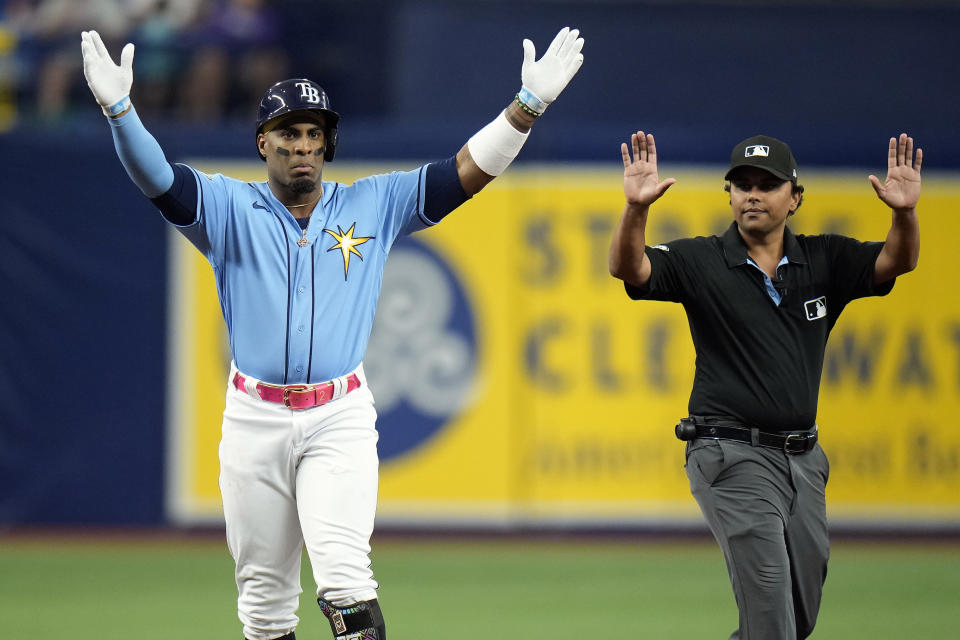 Tampa Bay Rays' Yandy Diaz, left, celebrates after his double off Colorado Rockies pitcher Ty Blach during the first inning of a baseball game Tuesday, Aug. 22, 2023, in St. Petersburg, Fla. Calling time out is second base umpire Erich Bachus. (AP Photo/Chris O'Meara)
