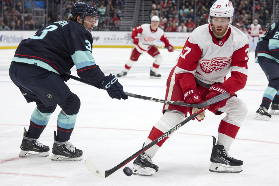 Detroit Red Wings right wing Daniel Sprong works to control the puck under pressure from Seattle Kraken center Yanni Gourde during the second period of an NHL hockey game, Monday, Feb. 19, 2024, in Seattle. (AP Photo/John Froschauer)