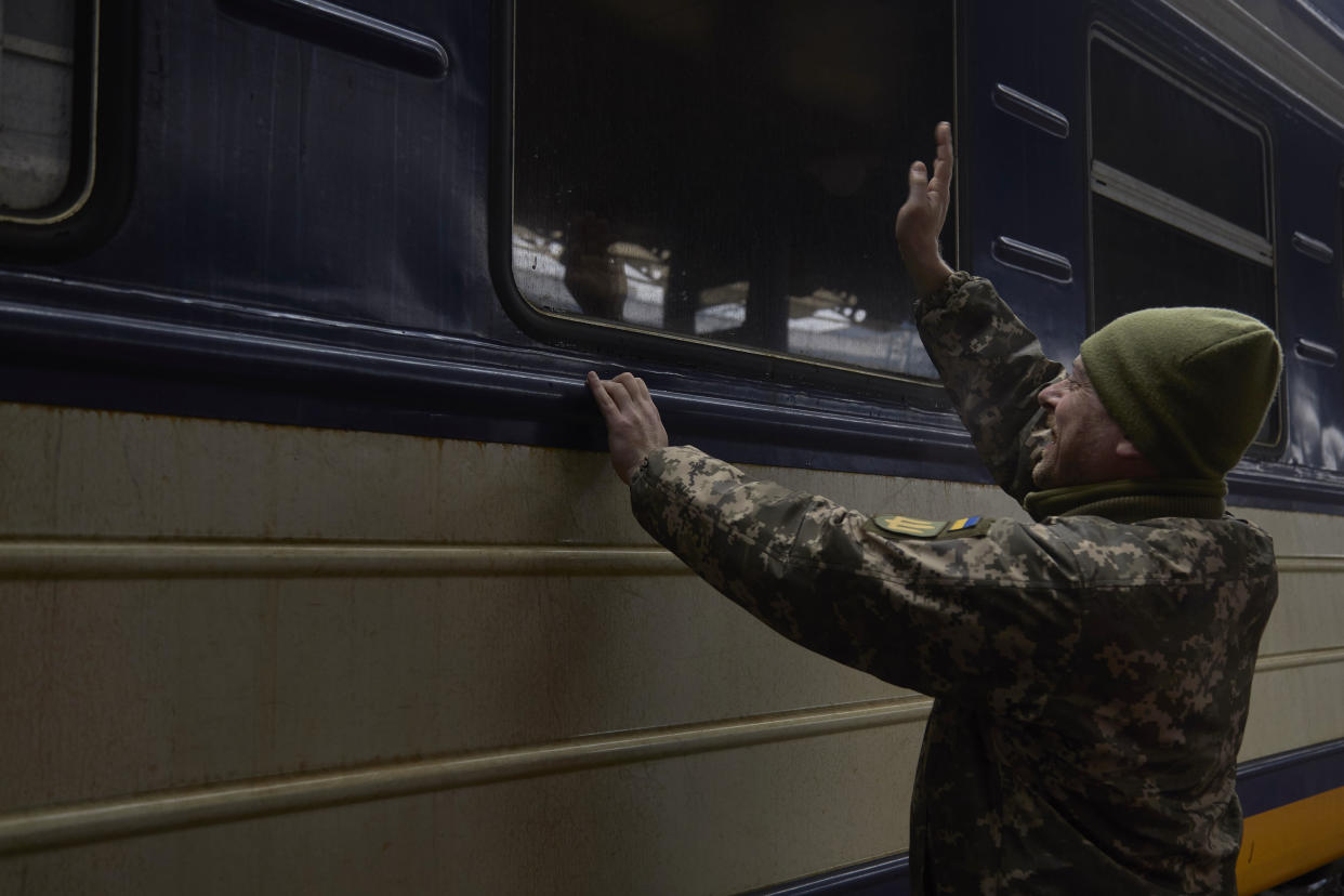 A Ukrainian serviceman waves goodbye to his family evacuating Kyiv on Thursday. 