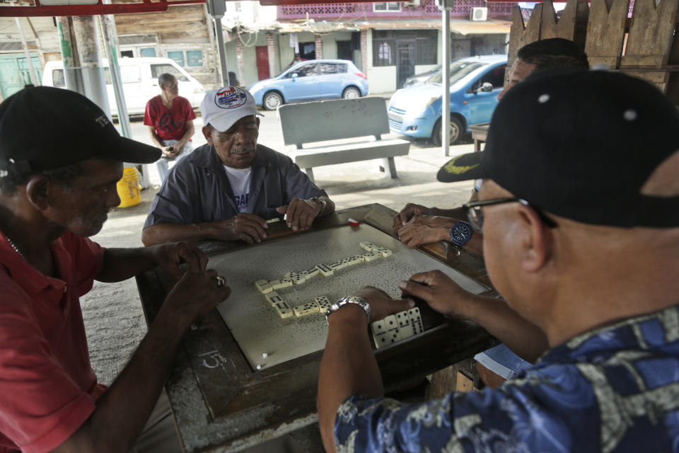 In this Dec. 1, 2019 photo, men play dominoes at "Parque de los Aburridos," or Park of the Bored, in the El Chorrillo neighborhood where former Gen. Manuel A. Noriega operated his headquarters and is an area that was bombed 30 years ago during the 1989 U.S. invasion in Panama City. Today this area still has desolate parts where residents say bombs fell, an iron light post pockmarked from bullets and graffiti with phrases like “Forbidden to forget” and “Dec. 20, national mourning.” (AP Photo/Arnulfo Franco)