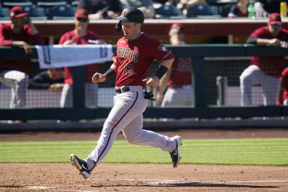 Arizona Diamondbacks' Daulton Varsho (12) arrives at home plate to score a run against the San Francisco Giants on a double hit by teammate David Peralta during the fifth inning of a spring training baseball game Wednesday, March 23, 2022, in Scottsdale, Ariz. (AP Photo/Ross D. Franklin)