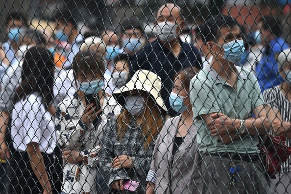 People wearing face masks gather at an outdoor area to take a swab test during mass testing for the COVID-19 coronavirus in Beijing.