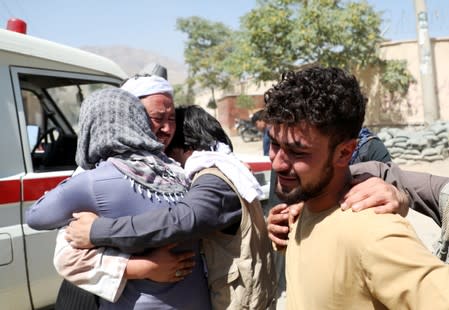 Afghan men comfort each other as they mourn during the funeral of their relatives after a suicide bomb blast at a wedding in Kabul