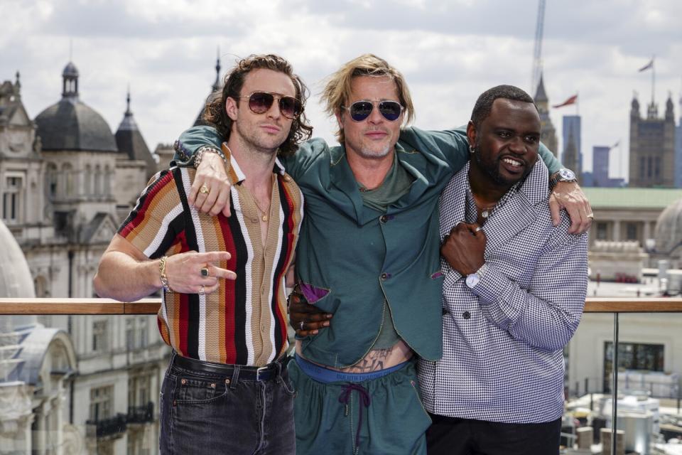 Three men stand together in front of a European skyline