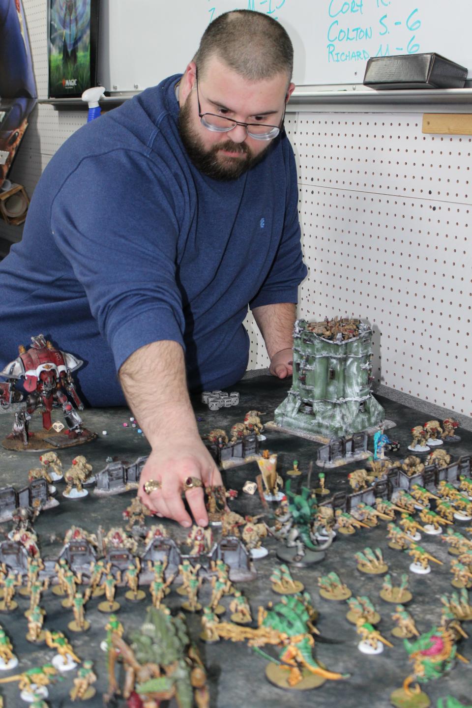 Monroe resident David Rousselo sets up his Warhammer 40,000, a miniature wargame, on one the back tables in the game room at Our House Games.