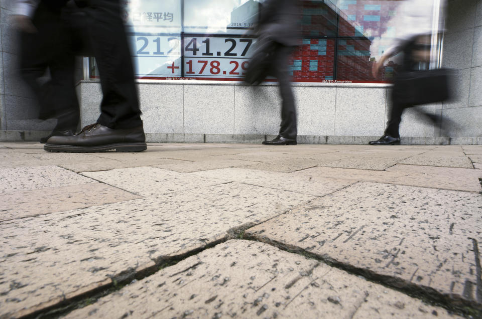 People walk past an electronic stock board showing Japan's Nikkei 225 index at a securities firm in Tokyo Friday, May 17, 2019. Asian stocks were mixed on Friday amid worries that U.S. economic sanctions on Huawei would put a drag on trade negotiations with China. (AP Photo/Eugene Hoshiko)