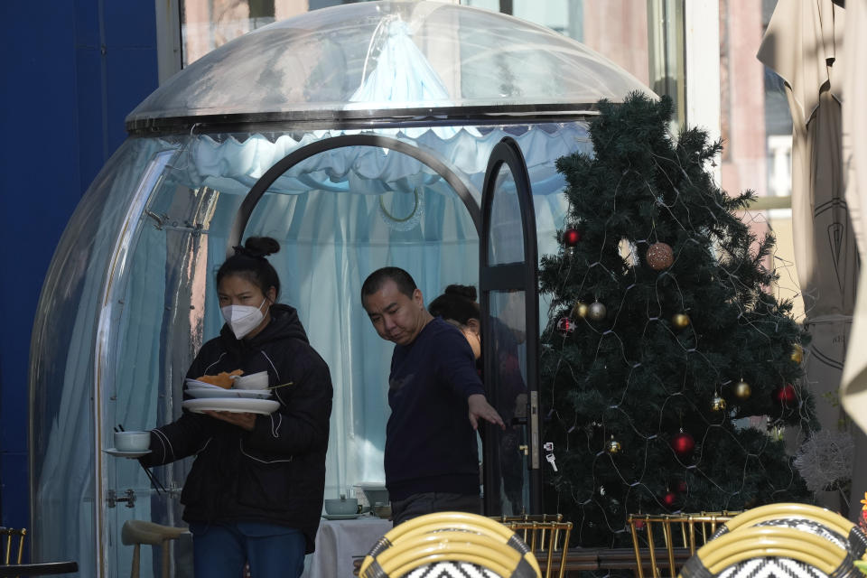 A workers clears dishes at a restaurant in Beijing, Tuesday, Dec. 27, 2022. Companies welcomed China's decision to end quarantines for travelers from abroad as an important step to revive slumping business activity while Japan on Tuesday announced restrictions on visitors from the country as infections surge. (AP Photo/Ng Han Guan)