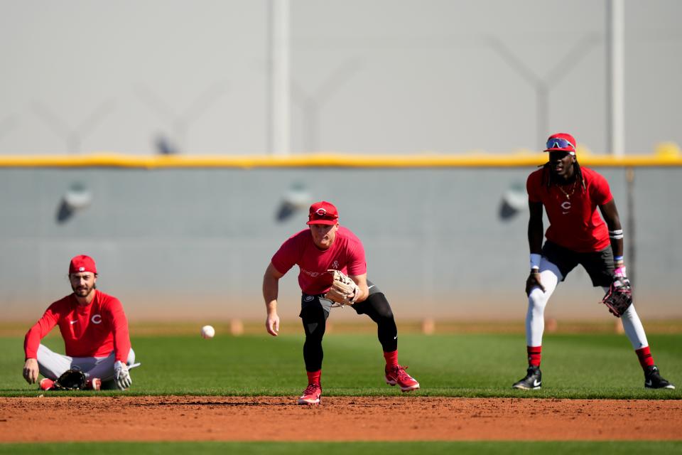 Cincinnati Reds shortstop Matt McLain (9) fields groundballs with Cincinnati Reds second baseman Jonathan India (6), left, and Cincinnati Reds third baseman Elly De La Cruz (44), right, during spring training workouts, Wednesday, Feb. 14, 2024, at the team’s spring training facility in Goodyear, Ariz.