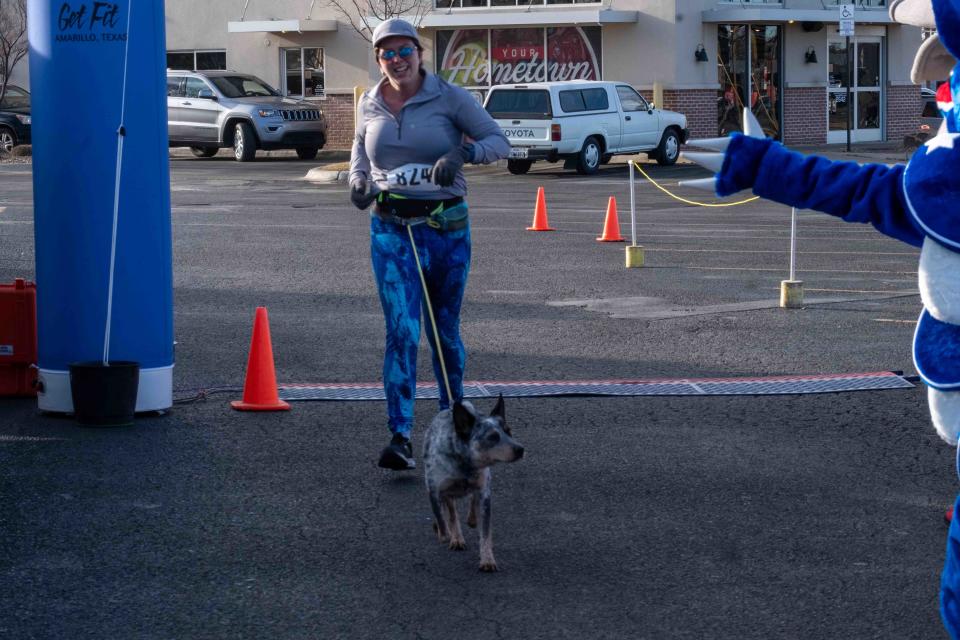 A runner and her unfazed dog cross the finish line Saturday morning at the Cold As Ice run in Amarillo.