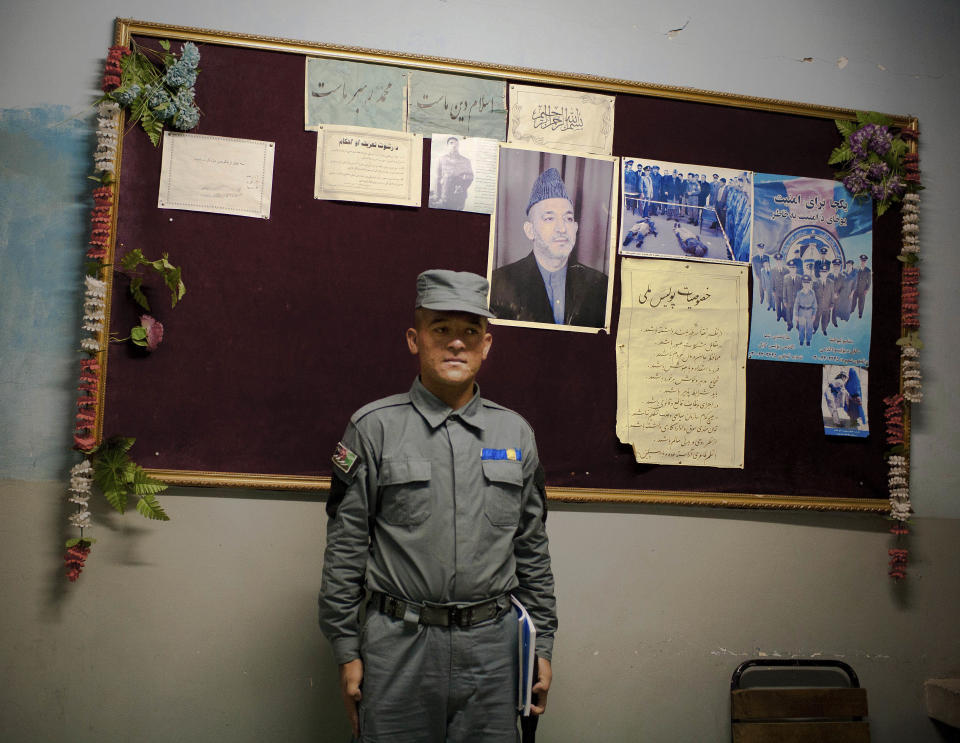 In this Oct. 15, 2012 photo, an Afghan police recruit stands in front of a board with announcements and a picture of Afghan President Hamid Karzai outside the sleeping quarters of the National Police Academy in Kabul, Afghanistan. Afghans go to the polls April 5, 2014 to choose a new president, and that in itself may one day be considered Karzai’s greatest achievement. (AP Photo/Anja Niedringhaus)