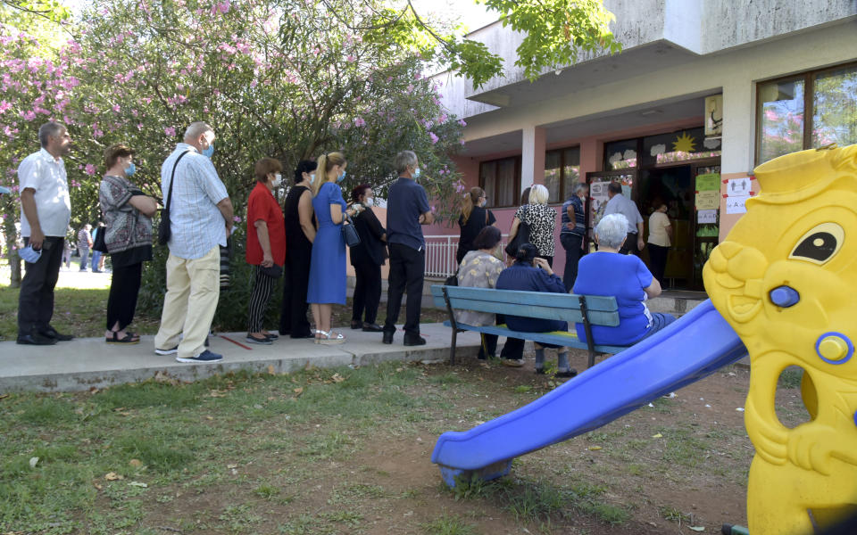 People wait in line at a poling station in Podgorica, Montenegro, Sunday, Aug. 30, 2020. Voters in Montenegro on Sunday cast ballots in a tense election that is pitting the long-ruling pro-Western party against the opposition seeking closer ties with Serbia and Russia. The parliamentary vote is marked by a dispute over a law on religious rights that is staunchly opposed by the influential Serbian Orthodox Church. (AP Photo/Risto Bozovic)