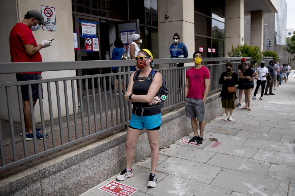 People wear masks as they wait in line to vote at a voting center during primary voting in Washington, Tuesday, June 2, 2020. (AP Photo/Andrew Harnik)