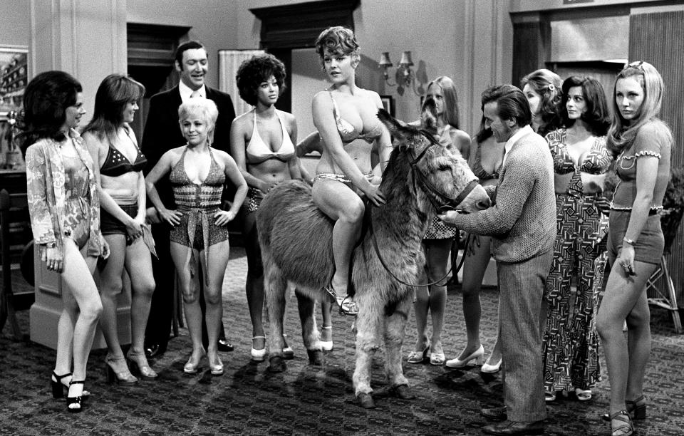 English actor Bernard Bresslaw (1934 - 1993) and actresses Wendy Richard and Barbara Windsor help orchestrate a beauty contest in the film 'Carry On Girls', 1973. Glamour model and actress Margaret Nolan is sitting astride the donkey. (Photo by Larry Ellis Collection/Getty Images)