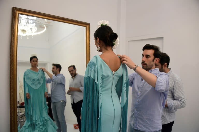 Le couturier espagnol Luis Fernández (c) ajuste une robe de flamenco sur sa cliente Virginia Cuaresma, dans son atelier de Séville, le 8 avril 2024 (CRISTINA QUICLER)