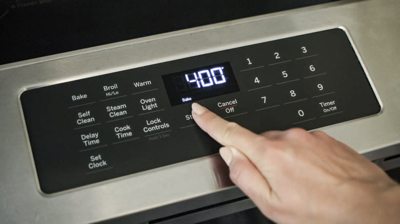 hand touching oven temperature gauge