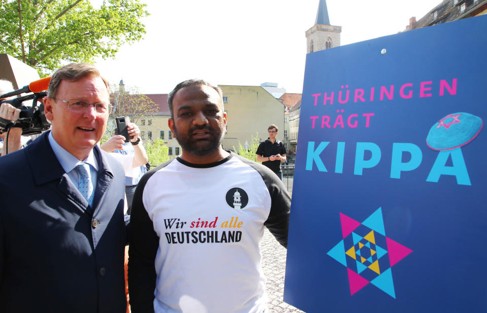 German politician Bodo Ramelow (L) and Mailk Mohamed Suleman from the Muslim Ahmadiyya community pose next to an ad for the 'Thuringia Wears Kippa' rally in Erfurt.