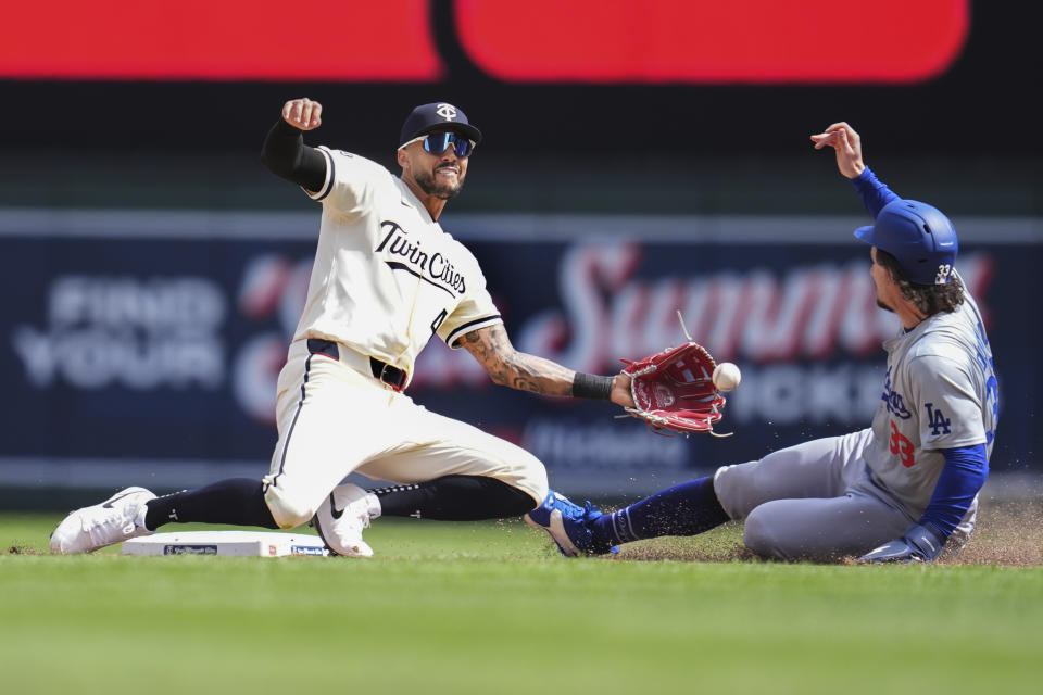 Minnesota Twins shortstop Carlos Correa, left, catches the throw from catcher Christian Vázquez to tag out Los Angeles Dodgers' James Outman attempting to steal during the sixth inning of a baseball game Wednesday, April 10, 2024, in Minneapolis. (AP Photo/Abbie Parr)