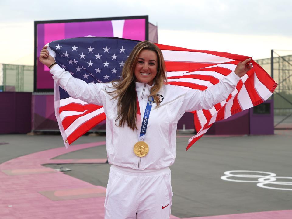 Amber English raises and American flag while wearing her gold medal at the Tokyo Olympics.