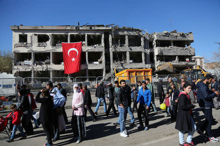 People walk past a police building, which was damaged during Friday's car bomb attack, in the Kurdish-dominated southeastern city of Diyarbakir, Turkey, November 5, 2016. REUTERS/Sertac Kayar