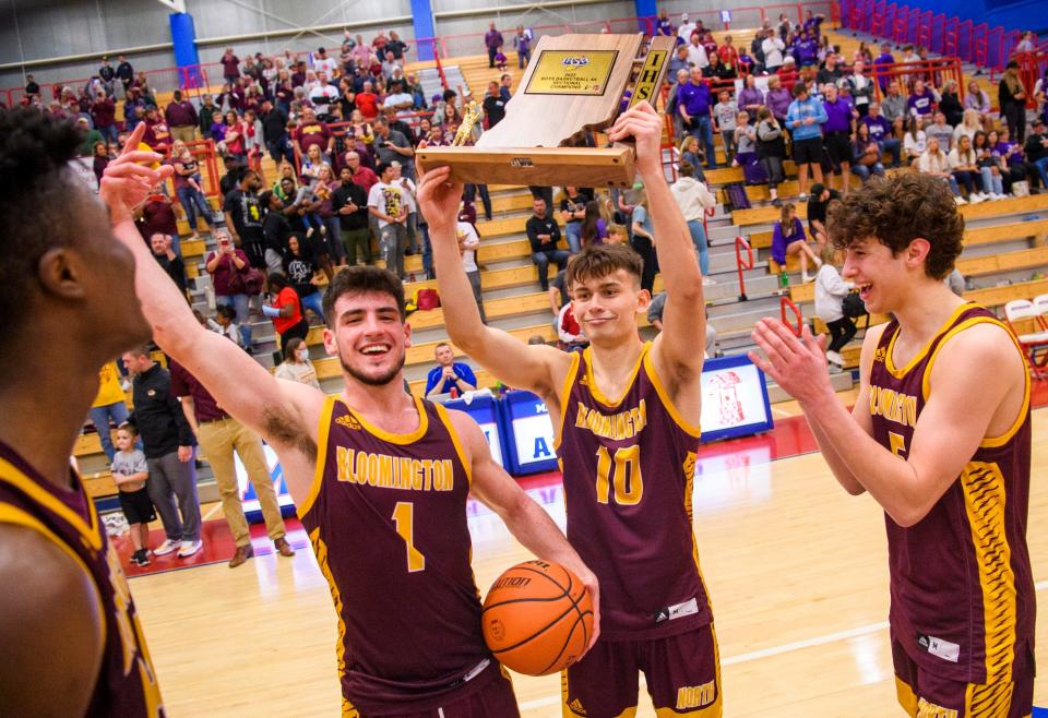 North's Marco Fitch (10) hoists the trophy as Nick Klaiber (1), JaQualon Roberts (24) and Nate Hoffman (5) celebrate winning the Bloomington North versus Bloomington South boys' basketball sectional final at Martinsville High School on Saturday, March 5, 2022. North won the game 32-28.