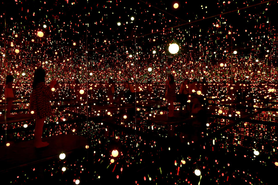 SINGAPORE - JUNE 06:  A visitor stands inside Japanese artist, Yayoi Kusama mirror, wooden panels, LED lights, metal, acrylic panels titled 'Infinity Room-Gleaming Lights of Souls' during a media preview at National Gallery Singapore on June 6, 2017 in Singapore. Yayoi Kusama: Life is the Heart of a Rainbow exhibition features over 120 works spanning 70 years of Kusama's artistic practise. The exhibition runs from June 9 to September 3, 2017.  (Photo by Suhaimi Abdullah/Getty Images)