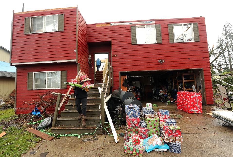 Hannah Mueller carries Christmas presents to the driveway of her parents' home as she helps salvage what they can after a tornado roared through Port Orchard, Wash., Wednesday, Dec. 19, 2018.  More bad weather is forecast for the weekend in the Pacific Northwest.