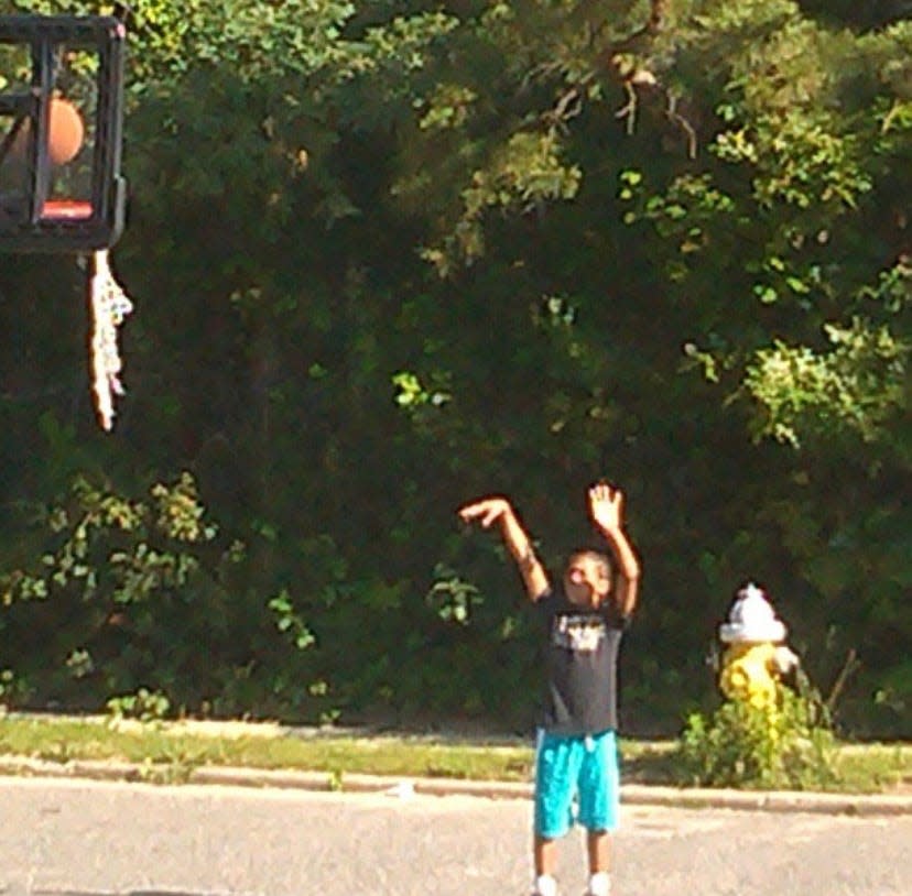 A young Zakai Zeigler shoots a basketball while waiting for the school bus in Brentwood, New York.