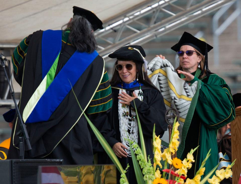 Amy Bowers Cordalis, center, a member of the Yurok Tribe and a University of Oregon graduate, receives a gift of a blanket during the Oregon commencement ceremony at Autzen Stadium in Eugene Tuesday, June 20, 2023.