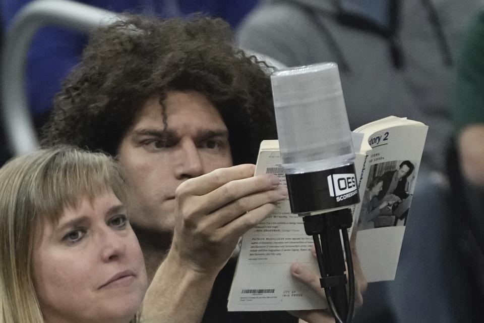 Milwaukee Bucks Robin Lopez reads a book during the first half of an NBA basketball game Thursday, Feb. 8, 2024, in Milwaukee. (AP Photo/Morry Gash)