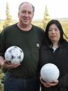 David Baxter (I) y su esposa Yumi, japonesa, posan con un par de balones, entre ellos el de fútbol que Baxter, un técnico de una estación de radar, encontró en la isla Middleton, un remoto lugar en el golfo de Alaska. Su esposa Yumi, por su parte, sostiene un balón de voleibol que encontraron y que tiene el nombre de una chica de 19 años, según afirma la NHK. REUTERS/Kyodo/FOR EDITORIAL USE ONLY. NO VENTAS