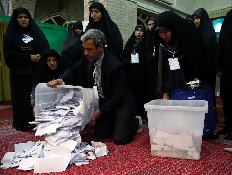 Poll workers empty full ballot boxes after the parliamentary election voting time ended in Tehran