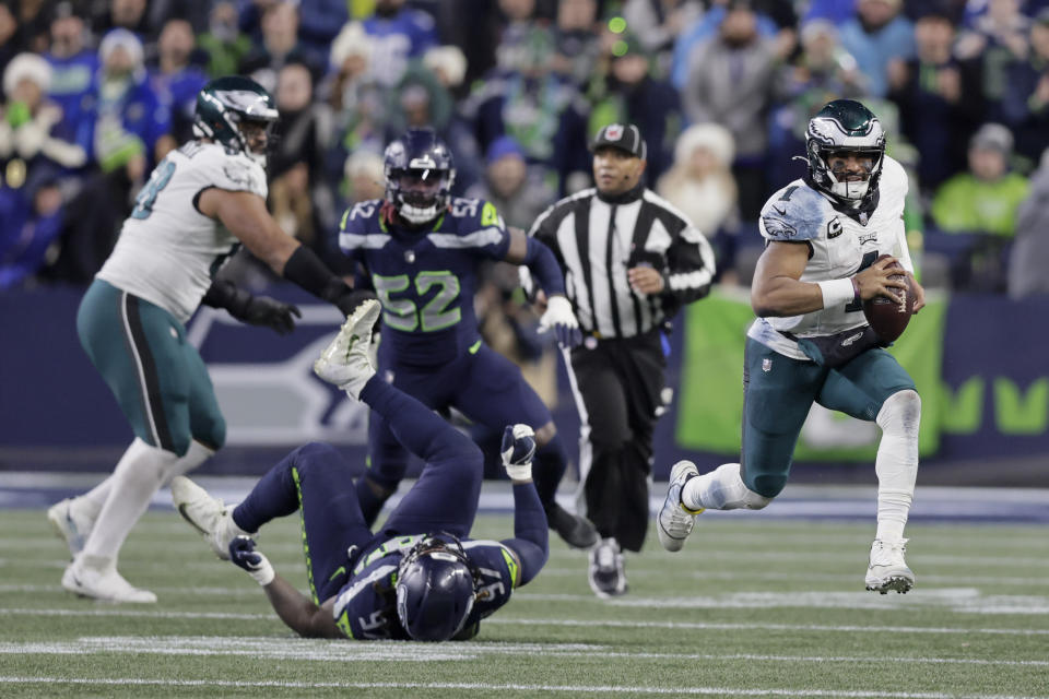 Philadelphia Eagles quarterback Jalen Hurts (1) scrambles for yardage as Seattle Seahawks defensive end Mario Edwards Jr. (97) falls to the ground 3during the first half of an NFL football game, Monday, Dec. 18, 2023, in Seattle. (AP Photo/John Froschauer)