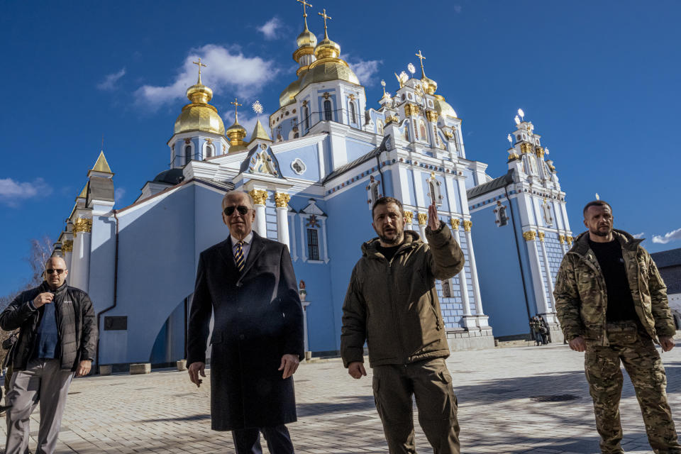 El presidente Joe Biden, a la izquierda en primer plano, es escoltado por el presidente de Ucrania, Volodímir Zelenski, en segundo plano, en su visita al Muro de la Memoria, un monumento a los soldados caídos del país, en Kiev, la asediada capital de Ucrania, el lunes 20 de febrero de 2023. (Daniel Berehulak /The New York Times).