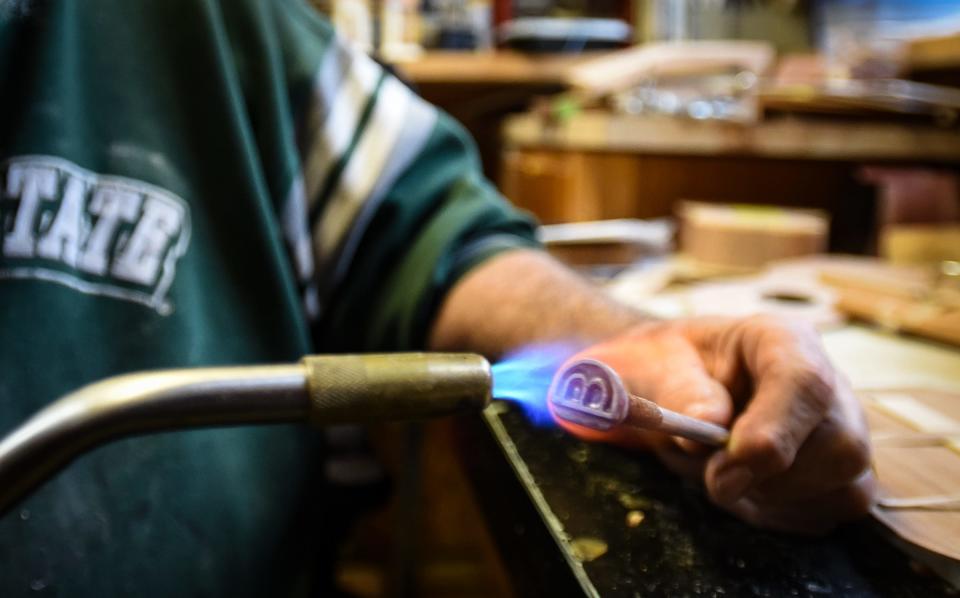 Musician and ukulele luthier Dave Birney heats up his custom branding iron that he'll burn into one of his handcrafted ukuleles, Wednesday, April 6, 2022, at his workshop in Mason.