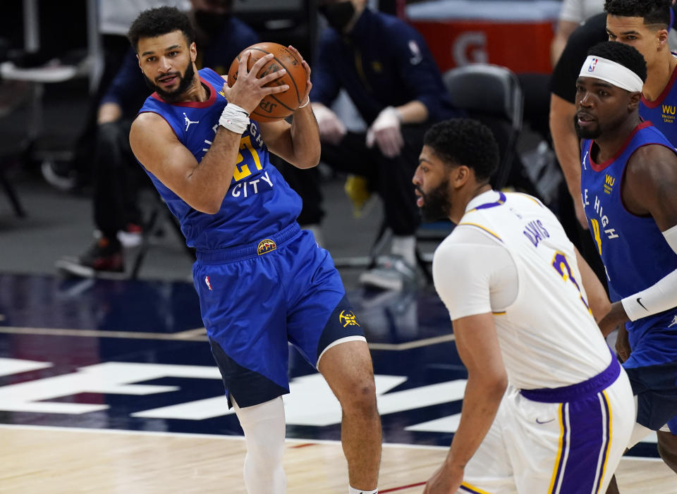 Denver Nuggets guard Jamal Murray, left, pulls in a rebound as Los Angeles Lakers forward Anthony Davis defends in the first half of an NBA basketball game Sunday, Feb. 14, 2021, in Denver. (AP Photo/David Zalubowski)