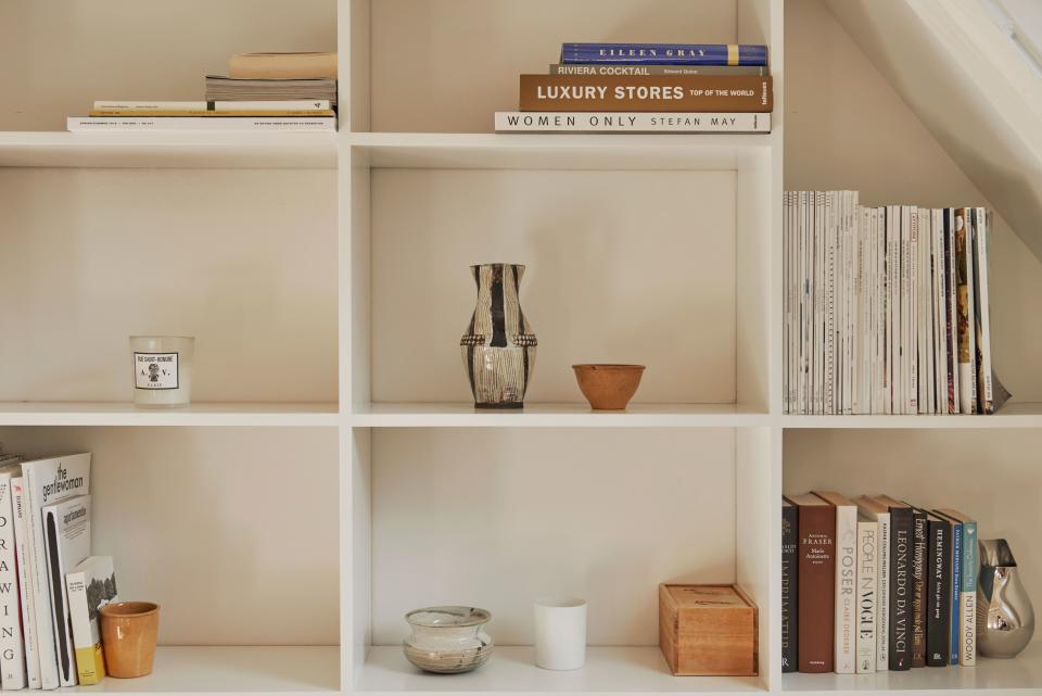A close-up of the shelves built by Steffan shows more organic tones and simplicity: an antique black-and-white ceramic pitcher, vases, bowls, a scented candle, and an Ilse Crawford for Georg Jensen silver jar—plus books, of course.