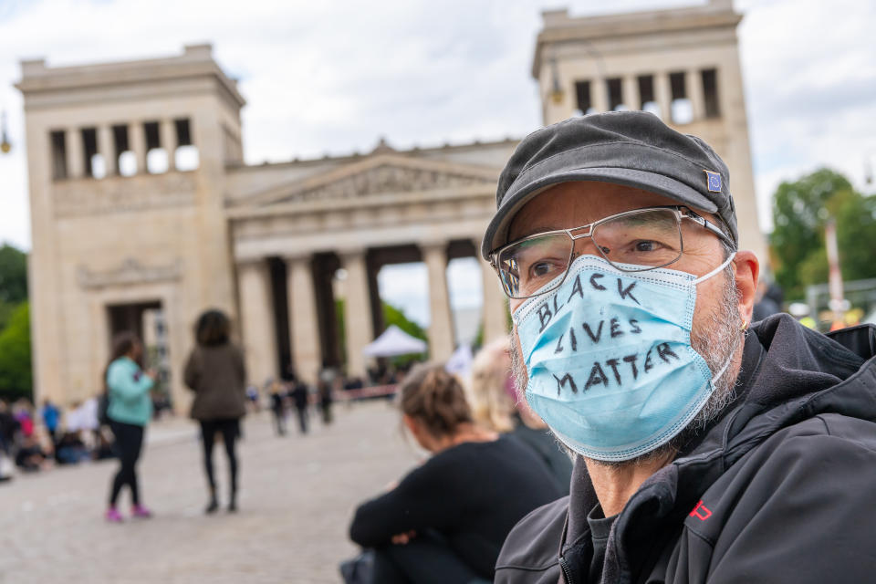 06 June 2020, Bavaria, Munich: A man wearing a face mask with the inscription "Black lives Matter" demonstrates against racism on the Königsplatz in the Bavarian capital during a "Silent Demo". The occasion is the violent death of George Floyd in the USA. A total of 25 German cities will be the venues for the demonstration. Photo: Peter Kneffel/dpa (Photo by Peter Kneffel/picture alliance via Getty Images)