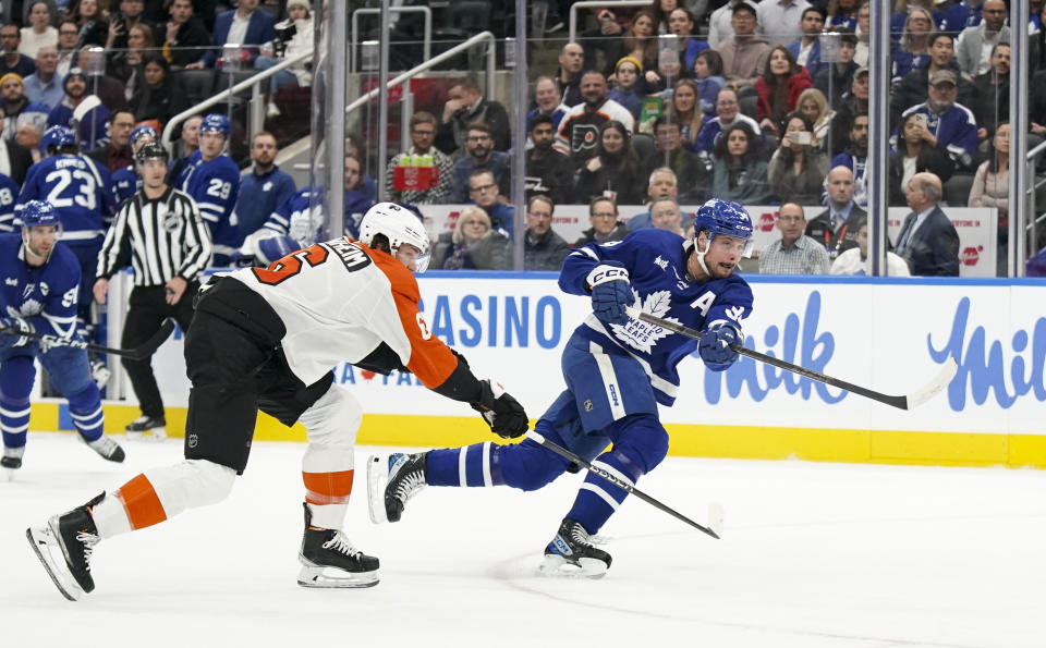 Toronto Maple Leafs center Auston Matthews (34) scores while being defended by Philadelphia Flyers defenseman Travis Sanheim (6) during the second period of an NHL hockey game Thursday, Feb. 15, 2024, in Toronto. (Arlyn McAdorey/The Canadian Press via AP)