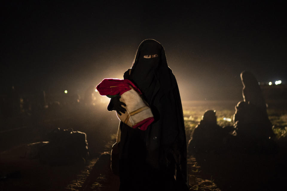 A woman and her baby, who were evacuated from the last territory held by Islamic State militants, walk after being screened by U.S.-backed Syrian Democratic Forces (SDF) in the desert outside Baghouz, Syria, on Feb. 25, 2019. (Felipe Dana / AP file)